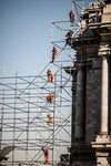 people in orange jumpsuits on tall scaffolding