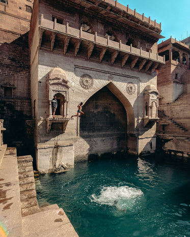 people jump into the water from a stone alcove