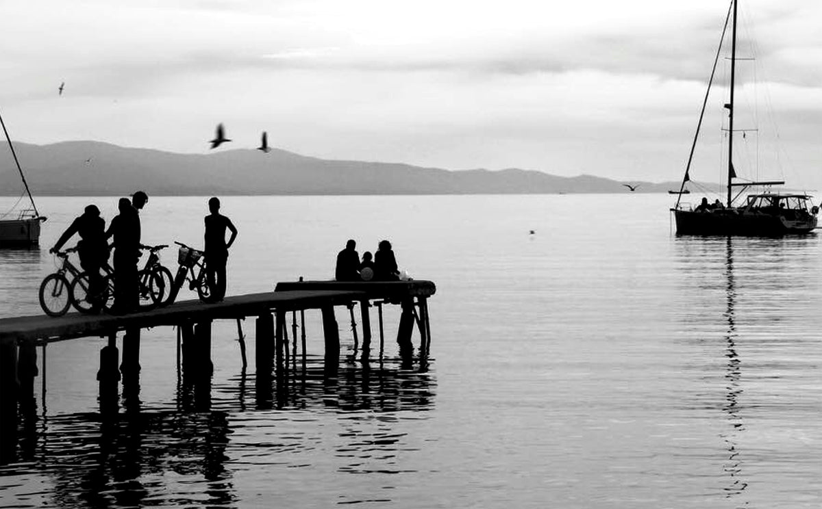 people on a dock and nearby boat in black and white