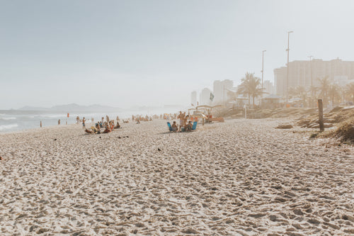 people on a sandy beach with city buildings