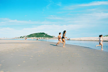 people run towards the water on a sandy beach