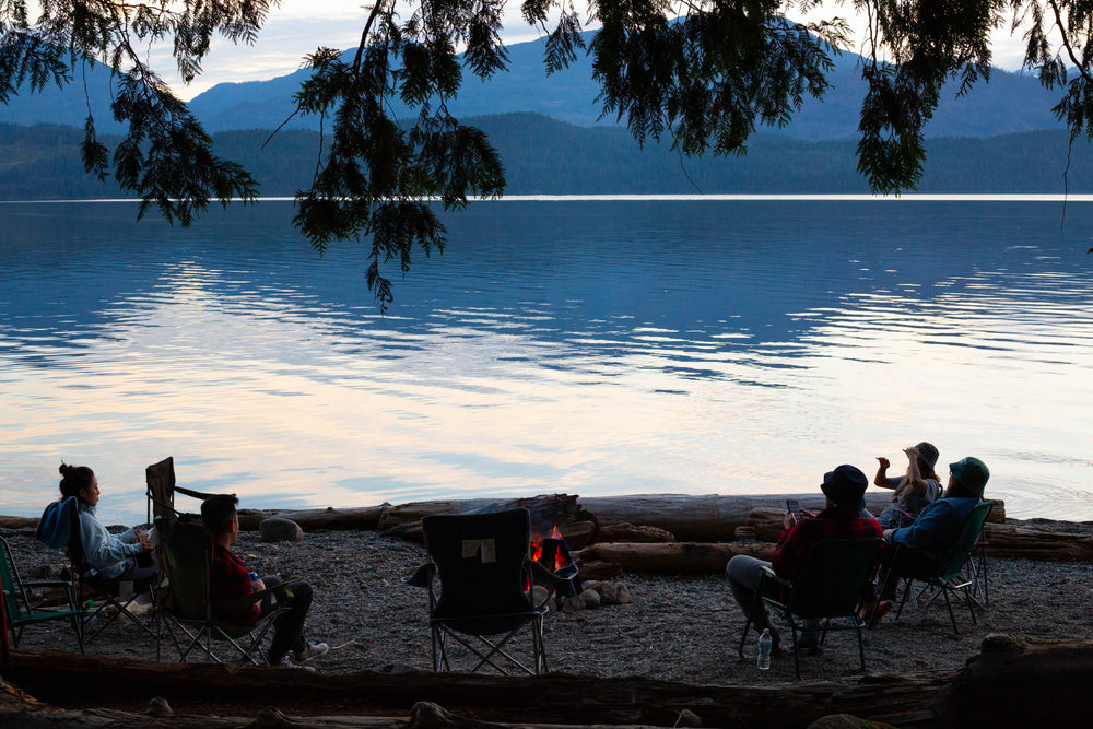 people sit around a bonfire on the beach