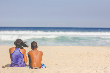 people sit on the beach and look out toward ocean