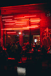 people sit outside building lit with red light
