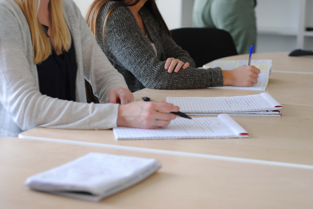 people sit with pads on lined paper and take notes