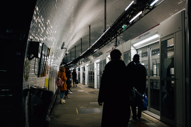 people stand waiting to board an underground train