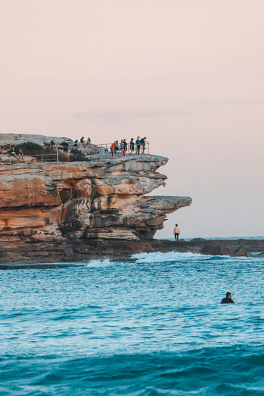 people view the water below from tall rocks