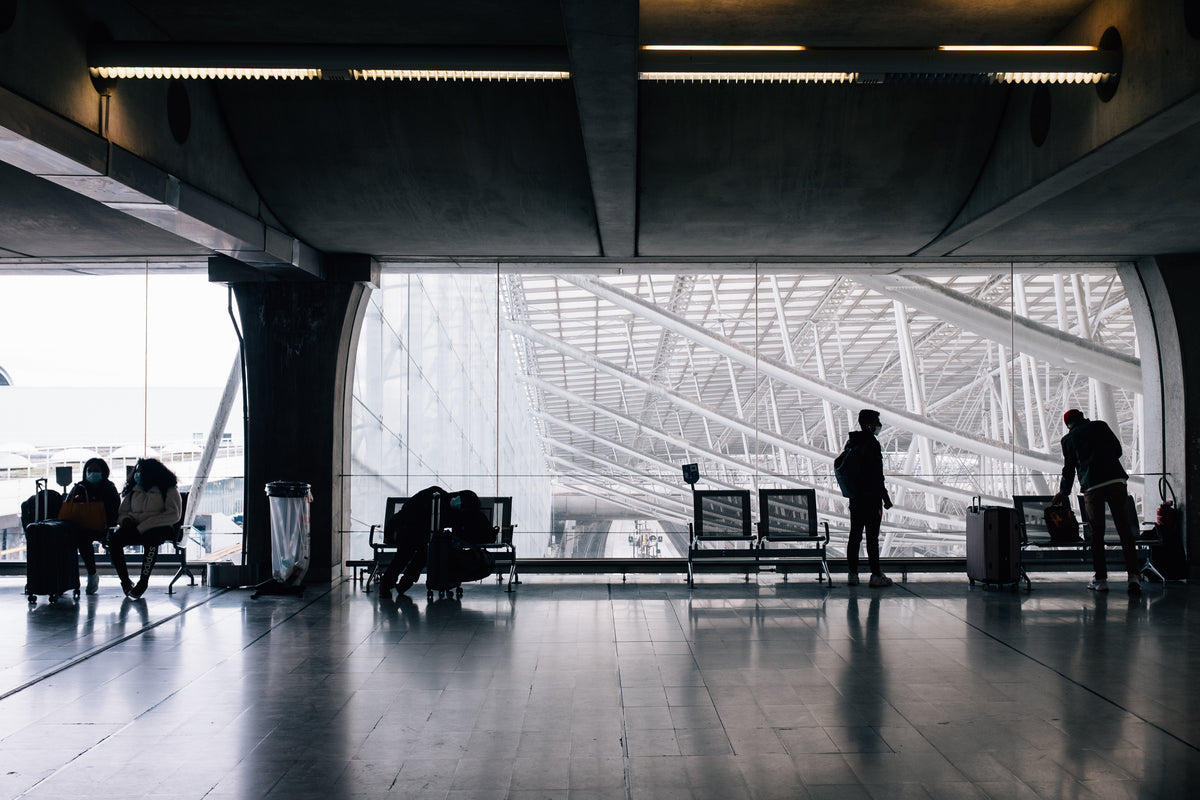 people wait to travel with luggage and face masks