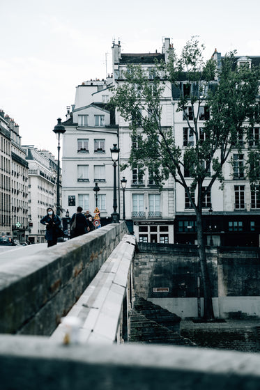 people walk a stone bridge near buildings