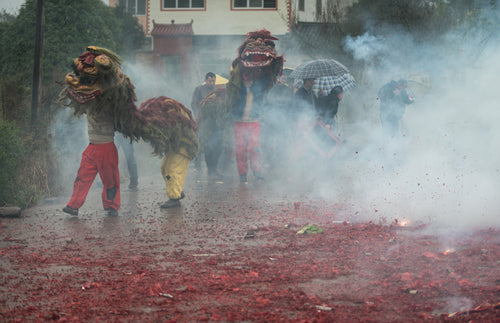 people walking down a foggy street with cloth dragons