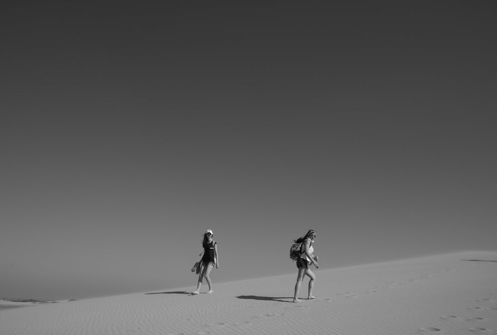 people walking in the desert in black and white