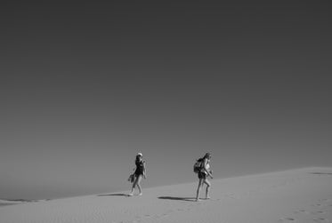 people walking in the desert in black and white