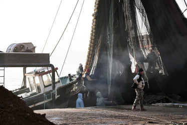 people working with nets and mast of a boat
