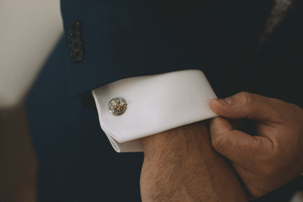 person adjusts cuff of a crisp white shirt