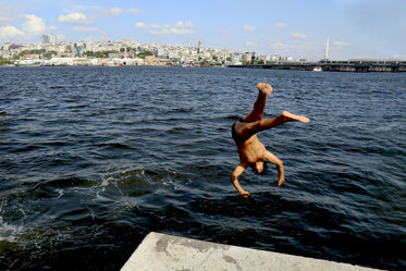 person captured mid air diving into a blue lake