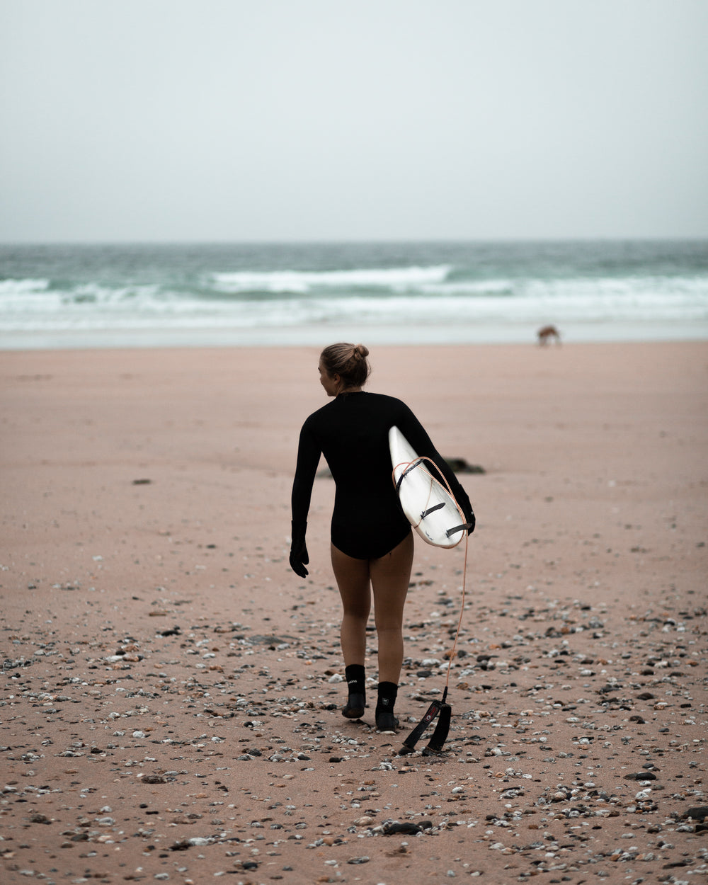 person carries surfboard on the beach