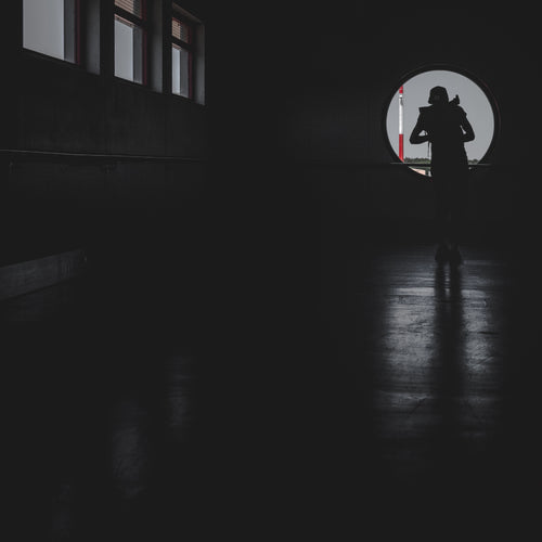 Person Cast In Shadows Looking From A Window