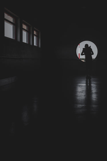 person cast in shadows looking from a window