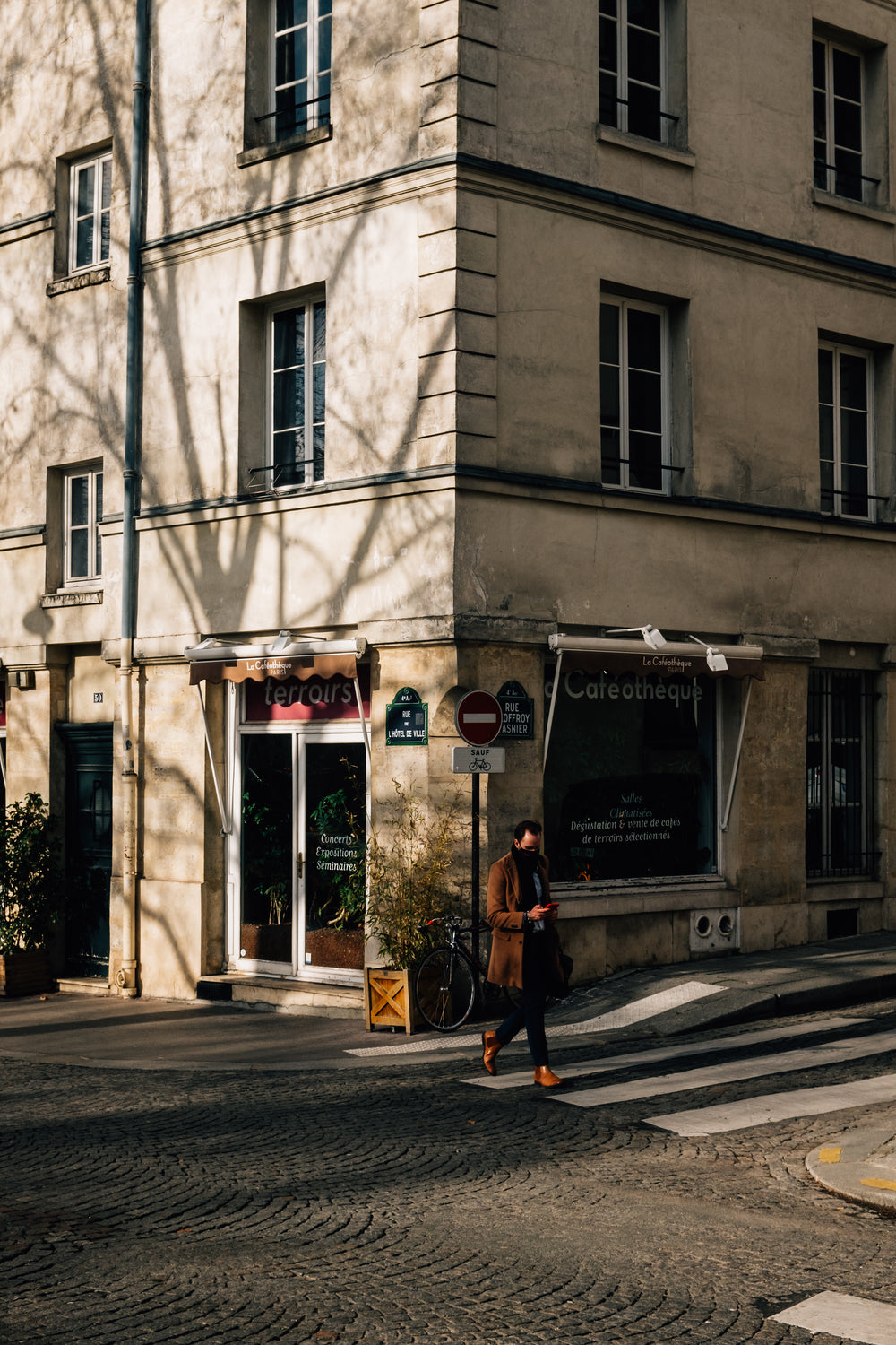 person crosses the street with white building behind