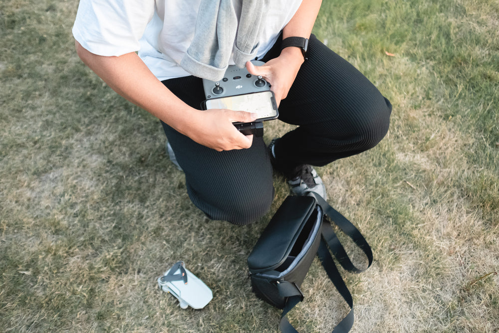 person crouches as they put the controls of a drone together