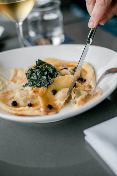 person cuts into plate of pasta