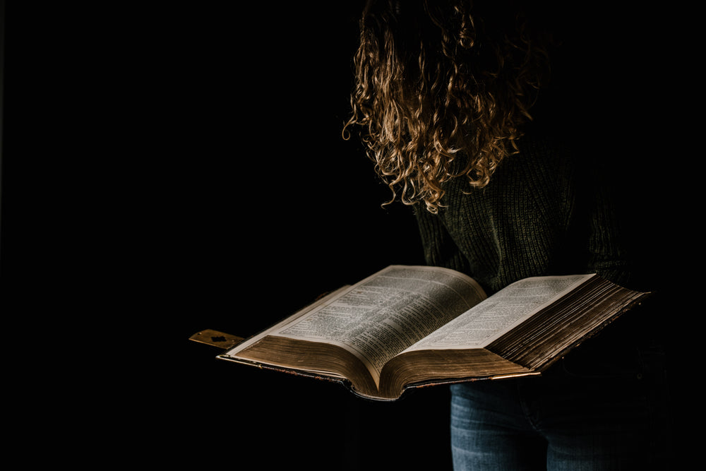 person dangles hair over gilded tome