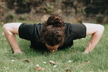 person does a push ups outdoors in the grass