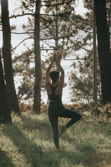 person does yoga pose outdoors surrounded by trees