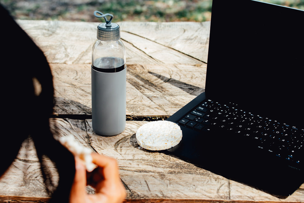 person eats rice cakes and works on there laptop outdoors