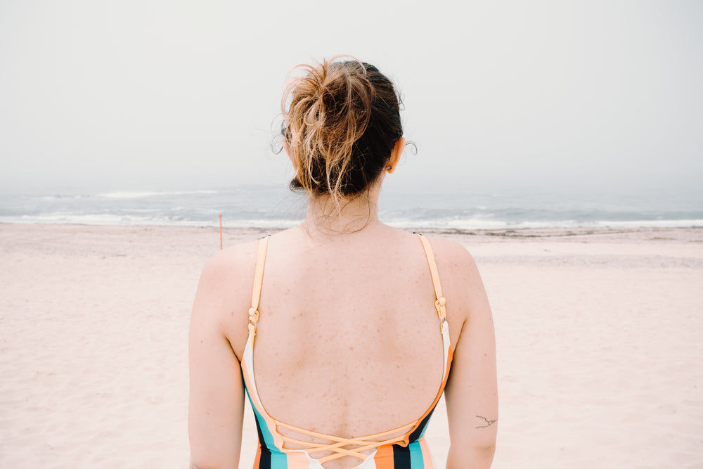 person facing wavy water on a sandy beach