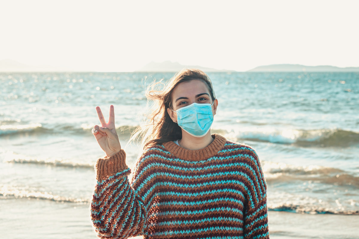 person gives peace sign while wearing a facemask