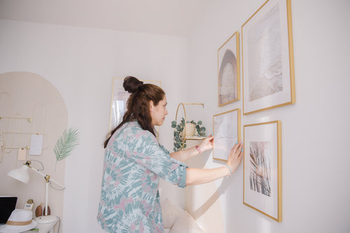 person hanging a wooden frame on a white wall
