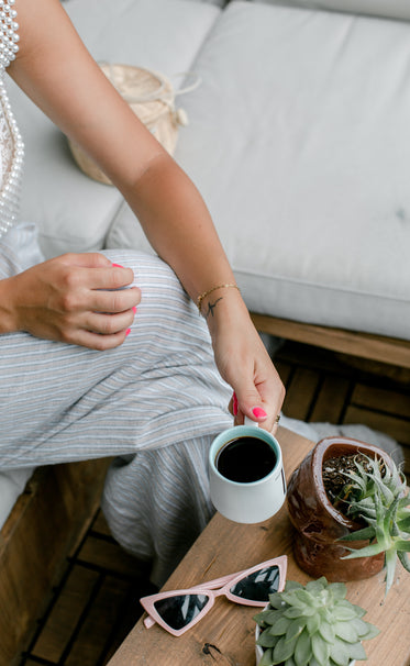 person hold a cup of coffee over wooden table