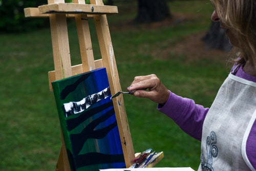 person hold a pallet knife to their painting