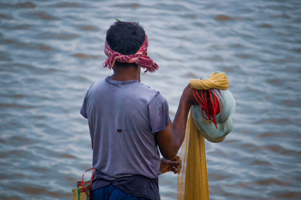 person holding a fishing net faces blue water