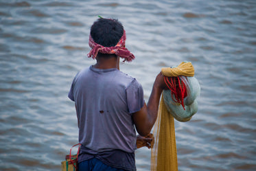 person holding a fishing net faces blue water