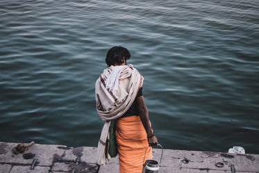 person holding a silver jug faces the wavy water