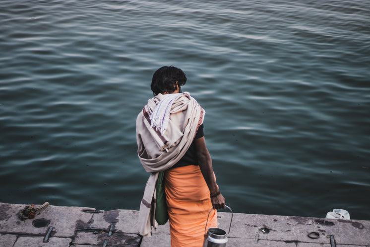 Person Holding A Silver Jug Faces The Wavy Water