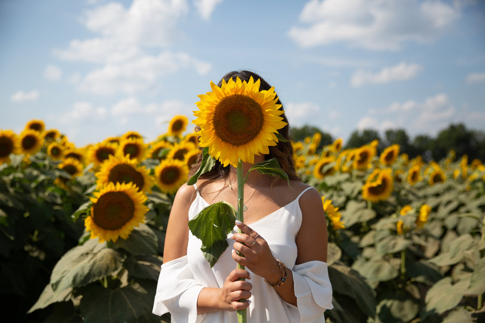 person holding a sunflower over their face