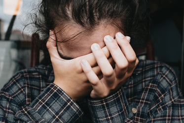 person holding their head in their hands close up