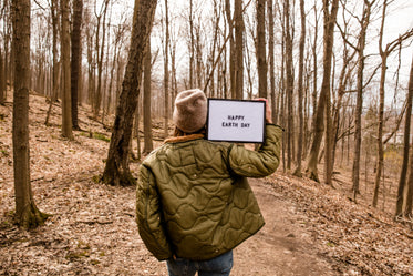 person holding up a sign in the forest for earth day