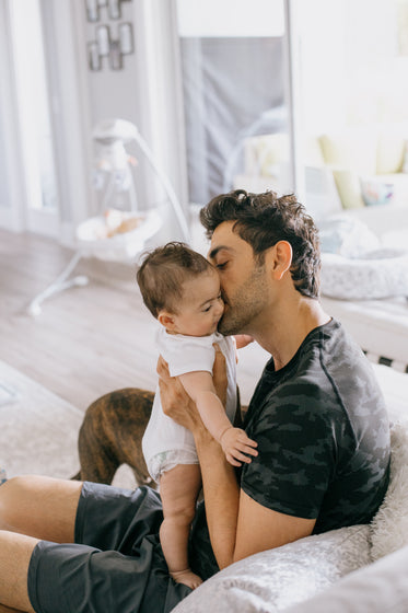 person holds a baby close and kisses their cheek