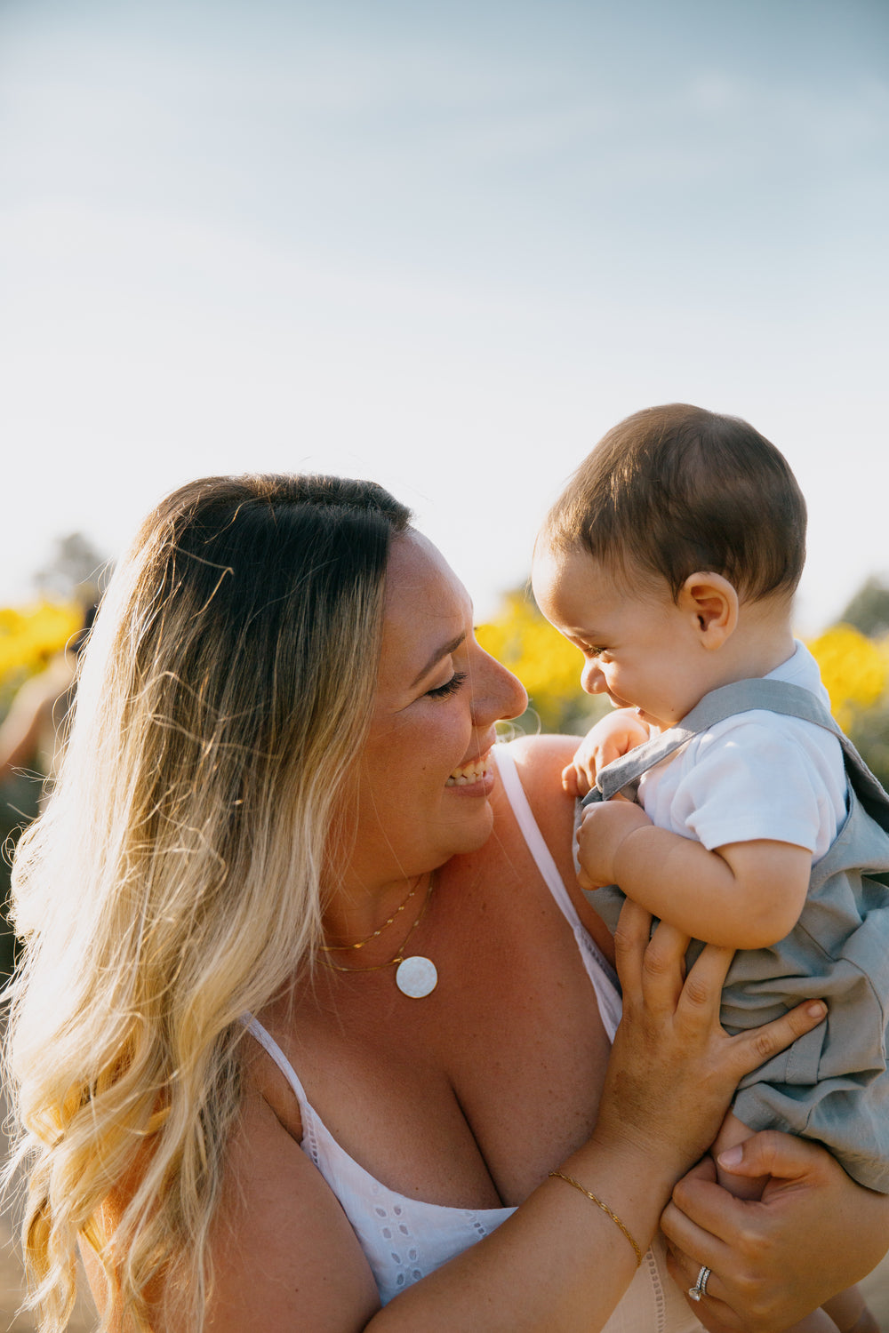 person holds a baby outside as they both giggle