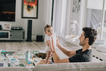 person holds a baby up while in their living room