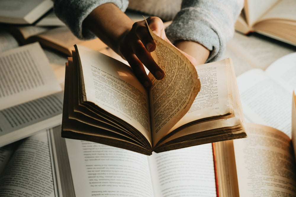  person holds a book over a stack and turns the page