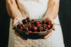 person holds a bowl of cherries out in front of them