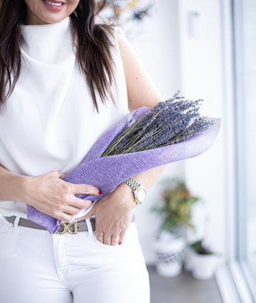 person holds a bundle of lavender wrapped in purple fabric