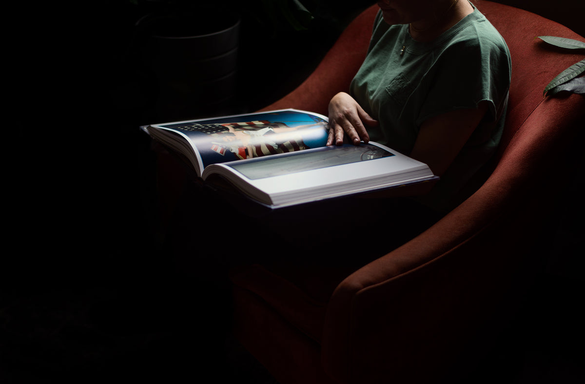 person holds a large book on their lap and reads