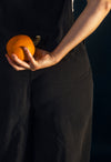 person holds a pumpkin behind their back