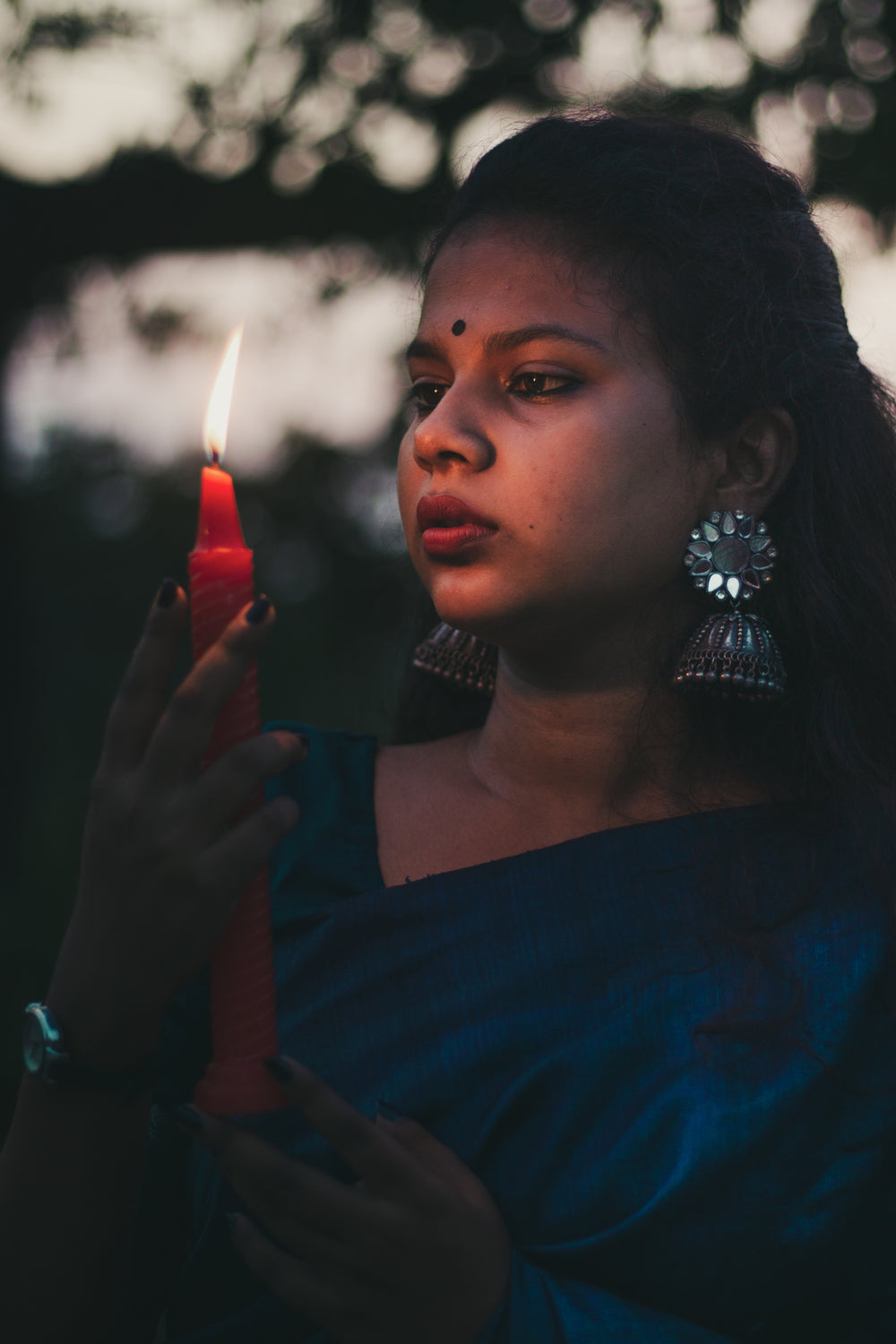 person holds a red candle stick that lights there face